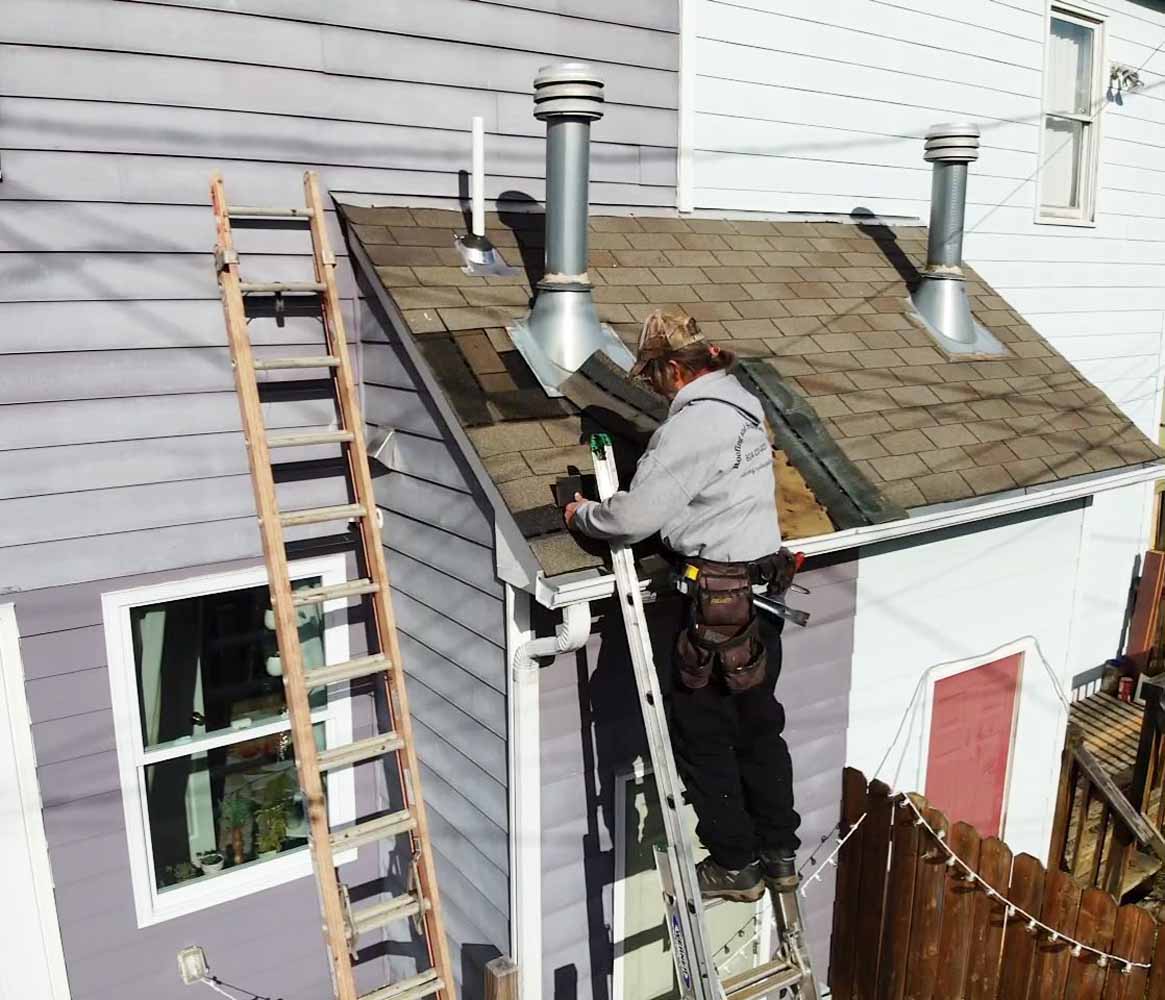 Hammersmith Roofing specialist on a ladder repairing roof shingles