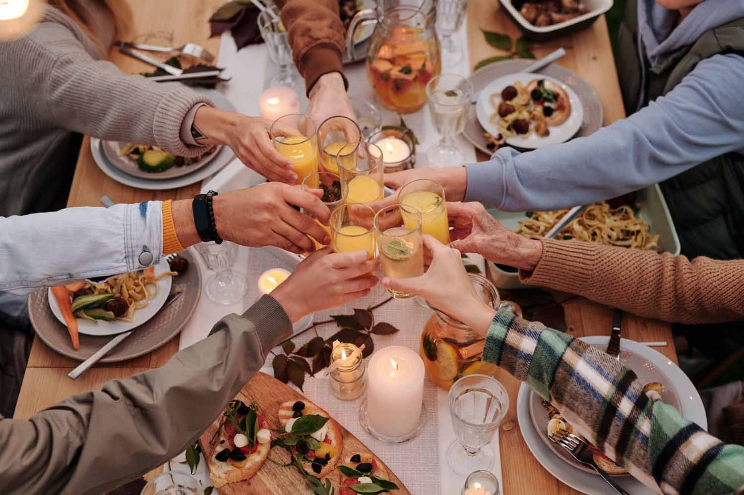 Faceless people toasting with glasses at dinner.