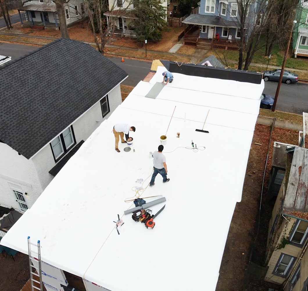 TPO membrane installation by 3 men on a residential flat roof