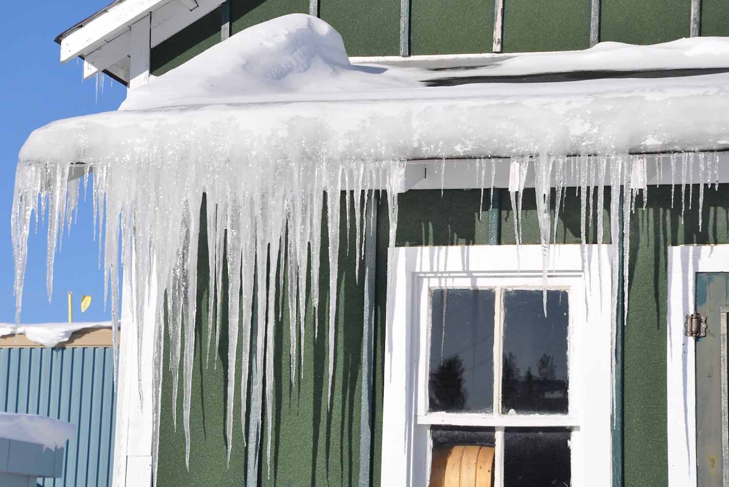Ice dam, icicles, and snow on the roof of a green house