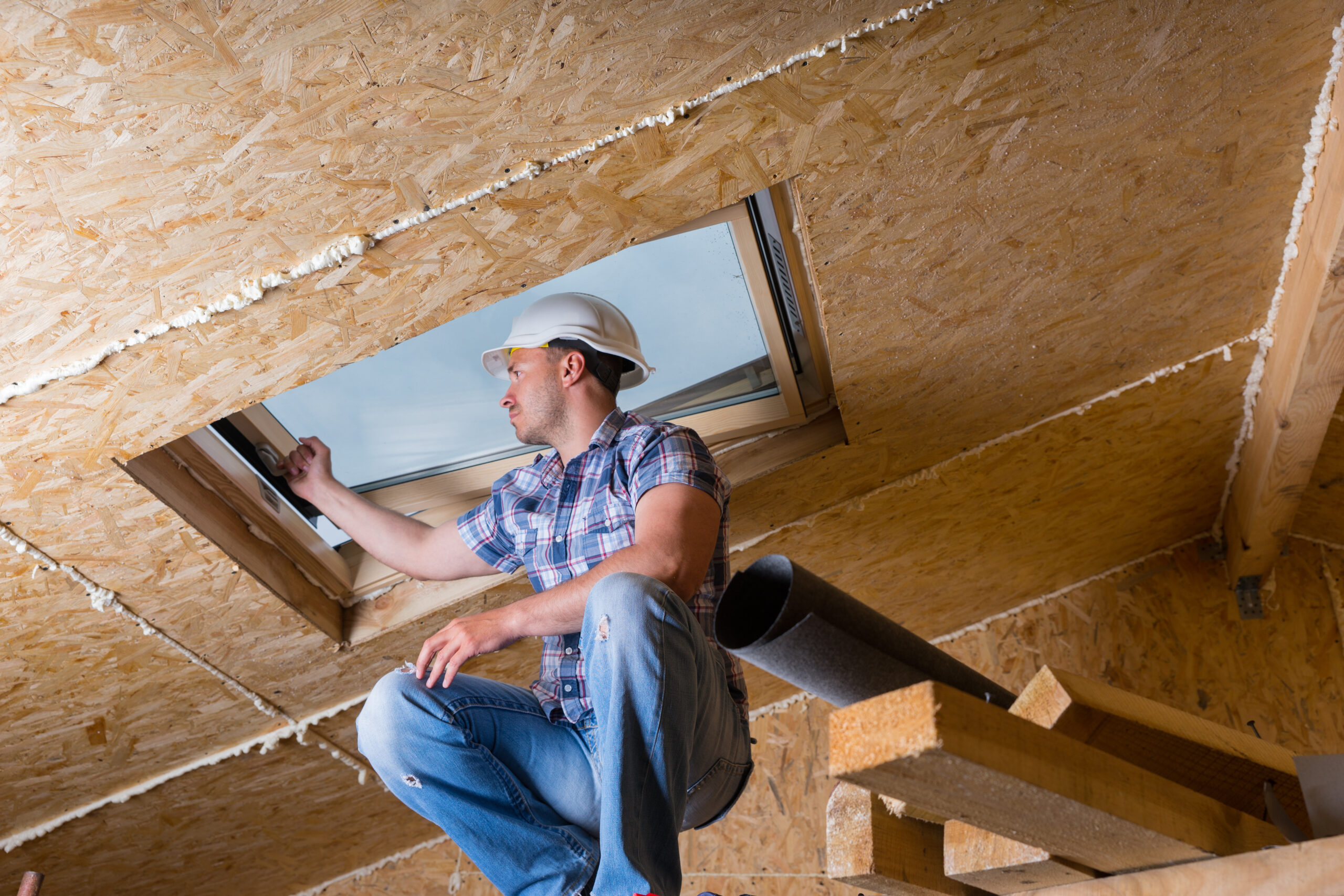 Man wearing a hardhat, installing a skylight