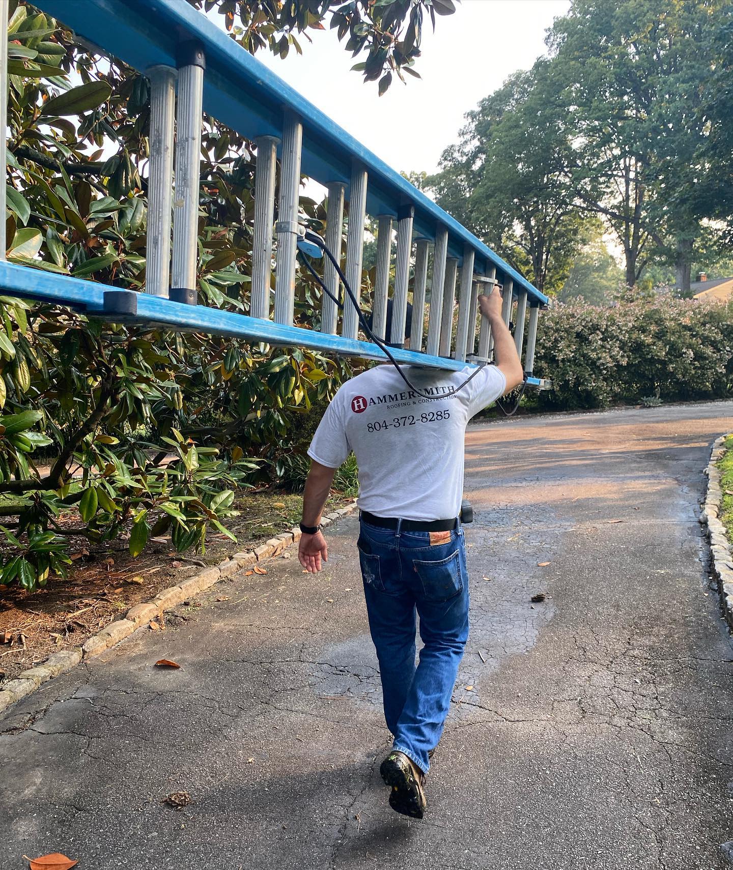 Hammersmith Roofing professional wearing a company branded shirt carrying a roofing ladder