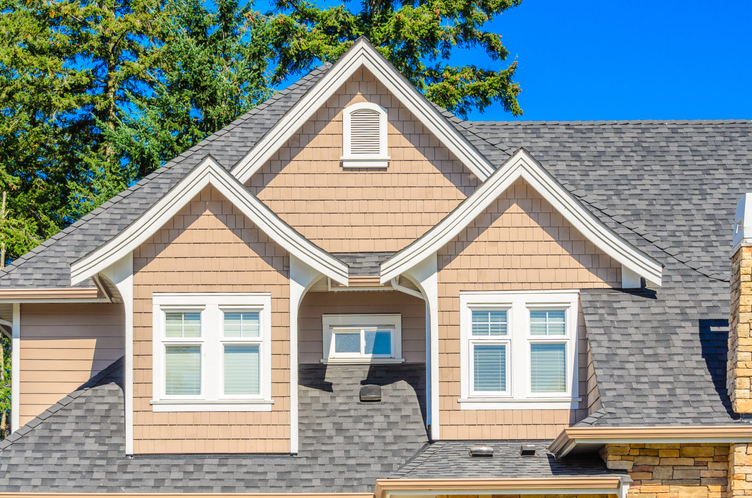 tan house with gray roof and multiple gables