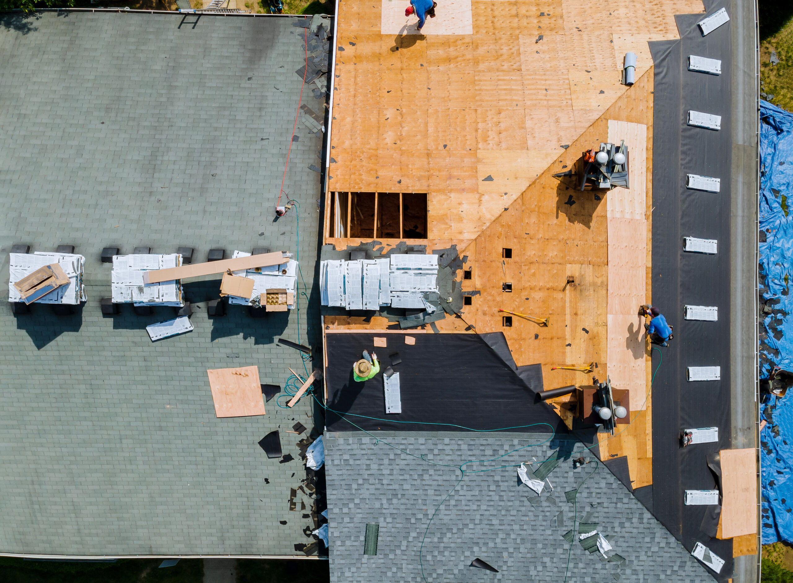 Aerial view of a large house with 2 roofers replacing the roof