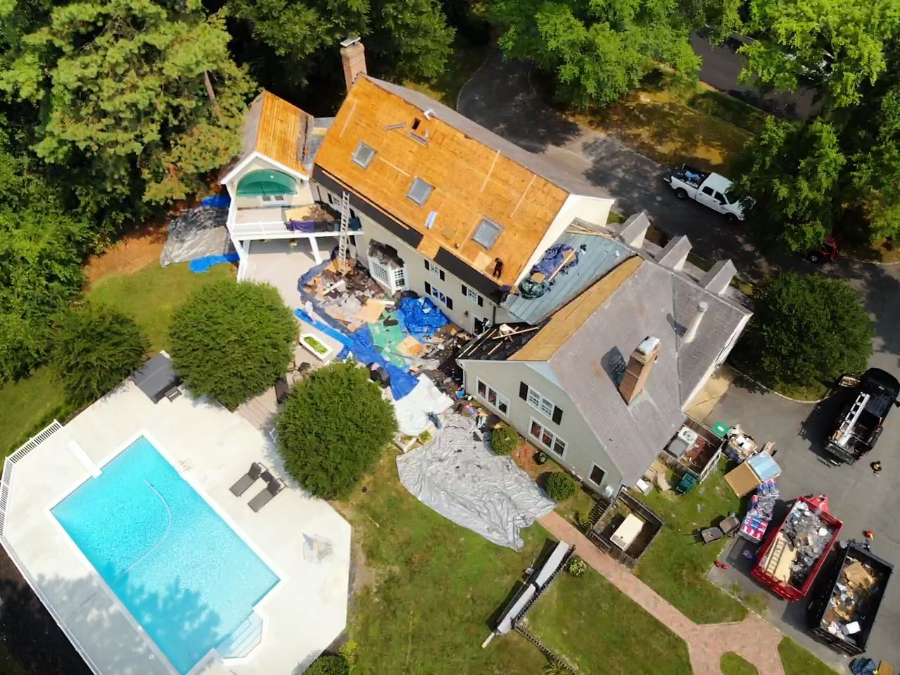 Roof replacement with old roofing on the ground and 2 full dumpsters