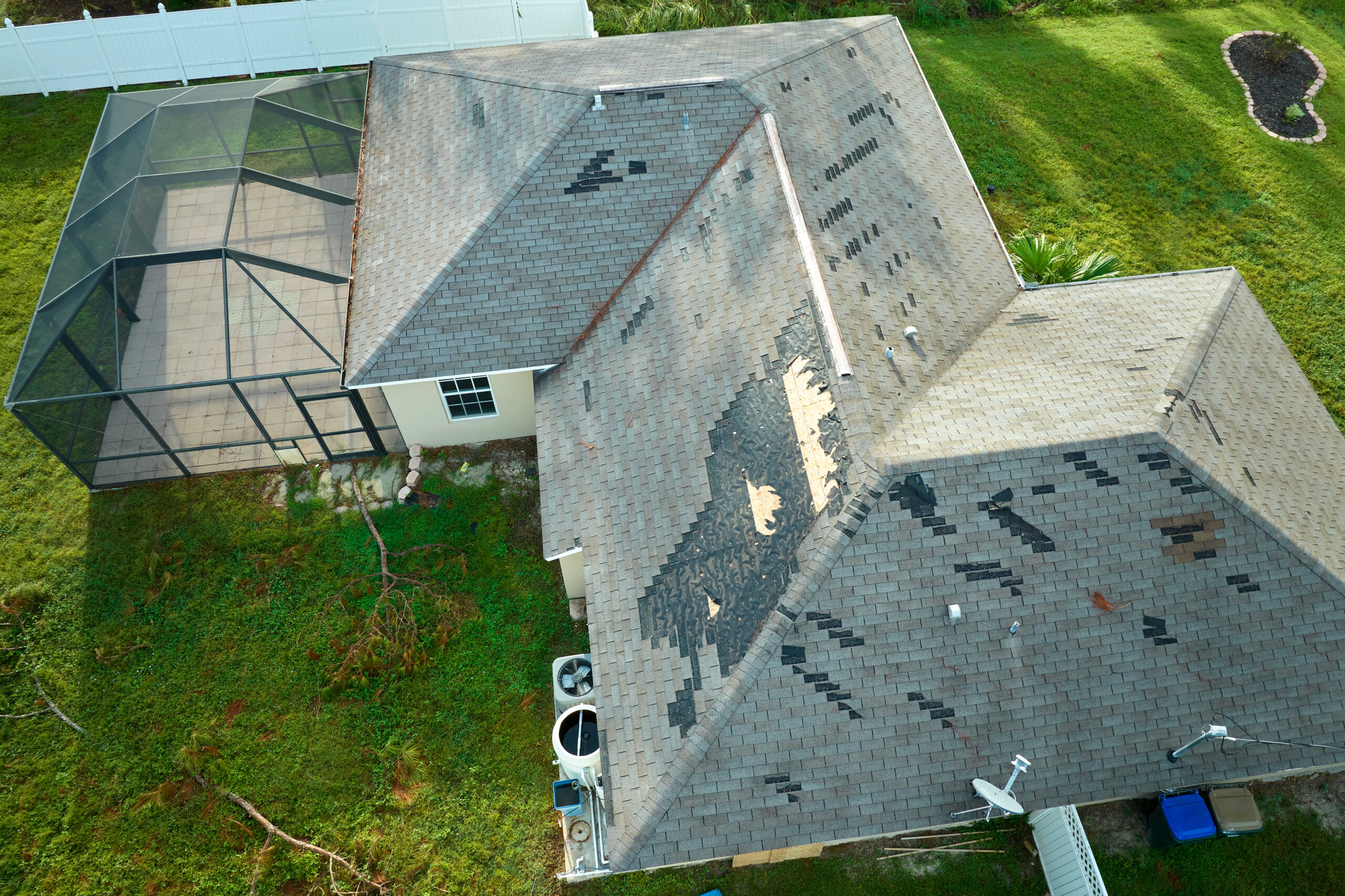 Wind damaged house roof with missing asphalt shingles after a natural disaster, hurricane.