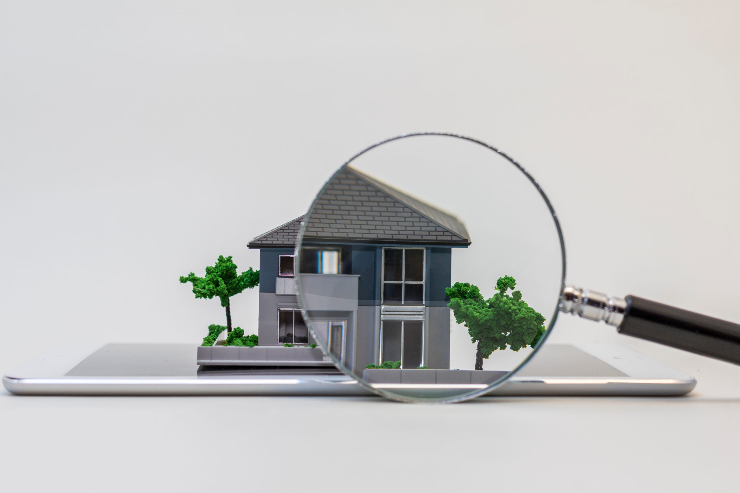 house miniature model on tablet pc and magnifying glass, roof inspection concept