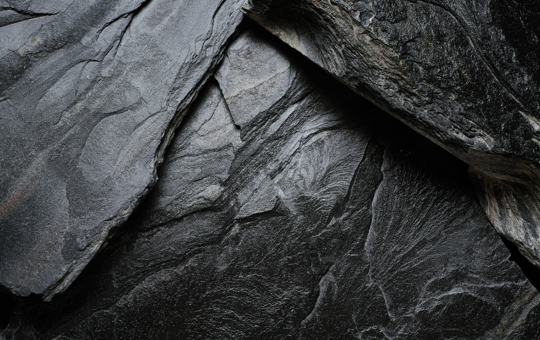 Close-up texture of dark slate rock with natural lines and rough surfaces. 