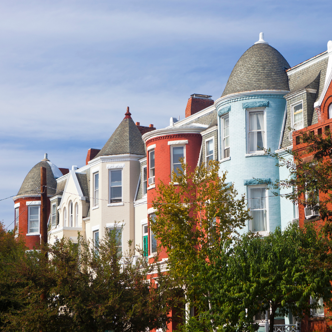 Row of colorful Victorian-style townhouses with turrets against a clear blue sky 