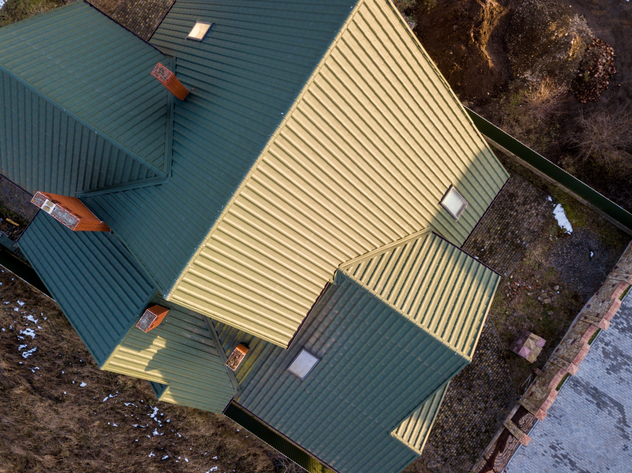 Aerial view of a green metal roof with multiple gables and intersecting ridges. 