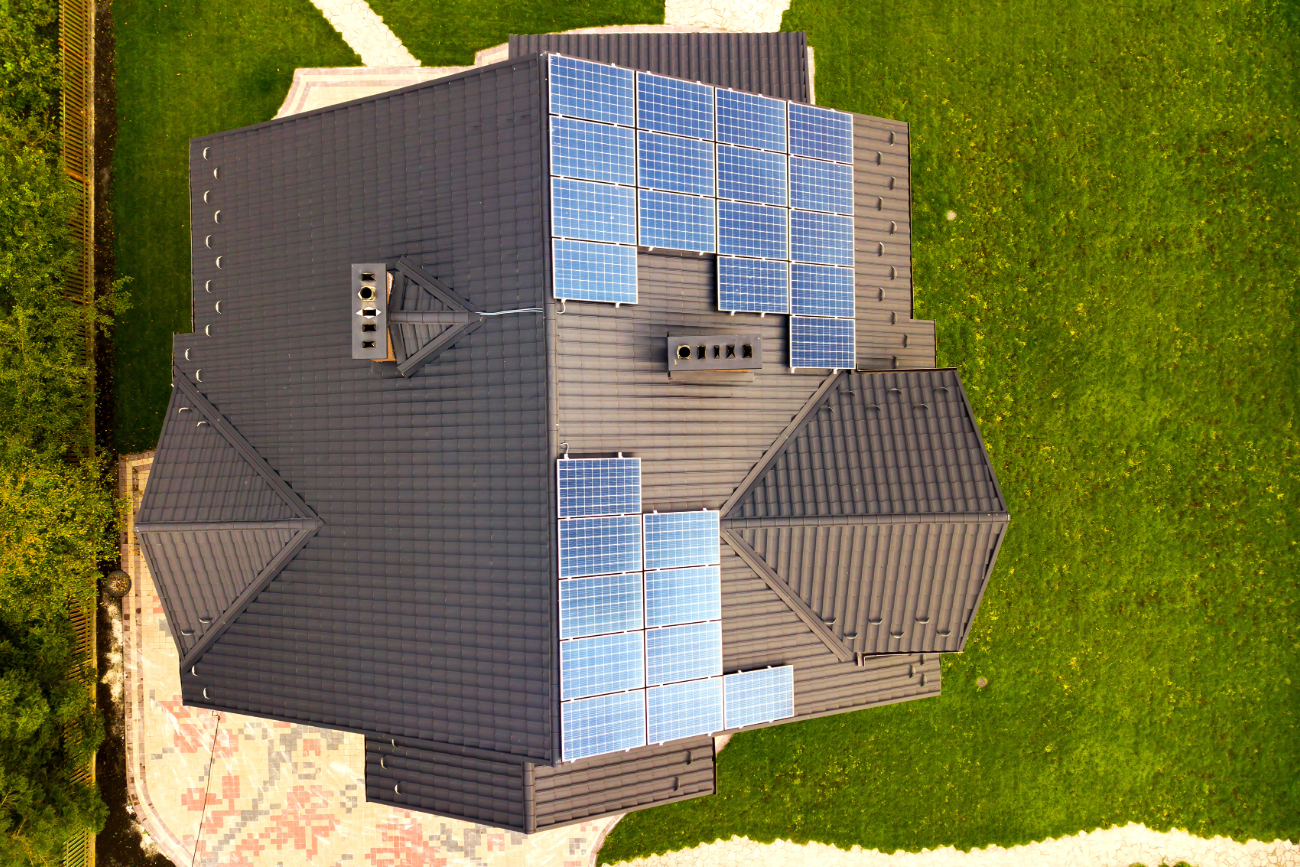 Aerial view of a grey roof with solar panels installed on one section. 