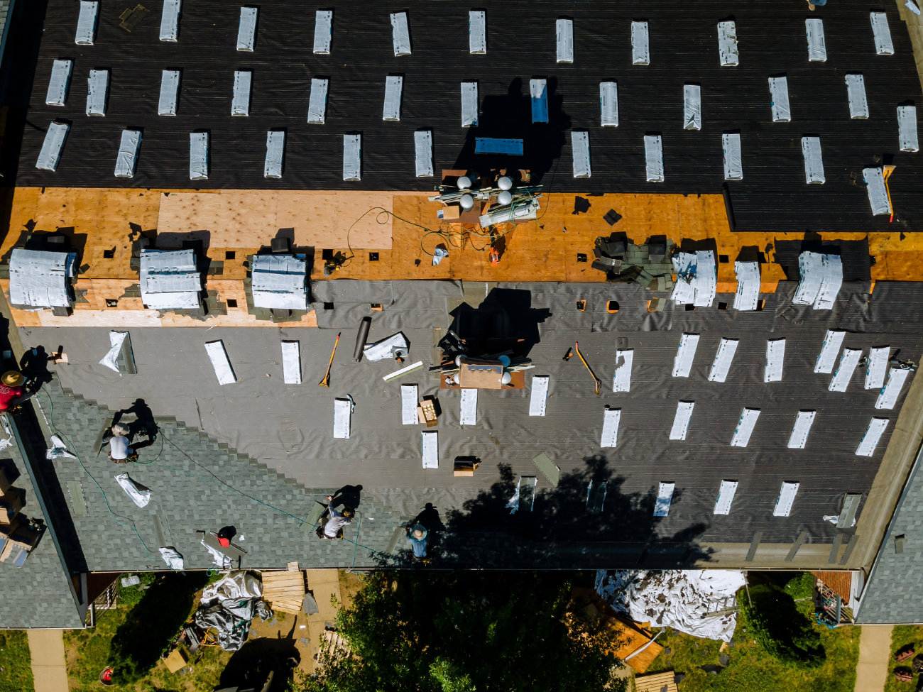 Aerial view of a commercial roofing project with workers and materials spread out. 