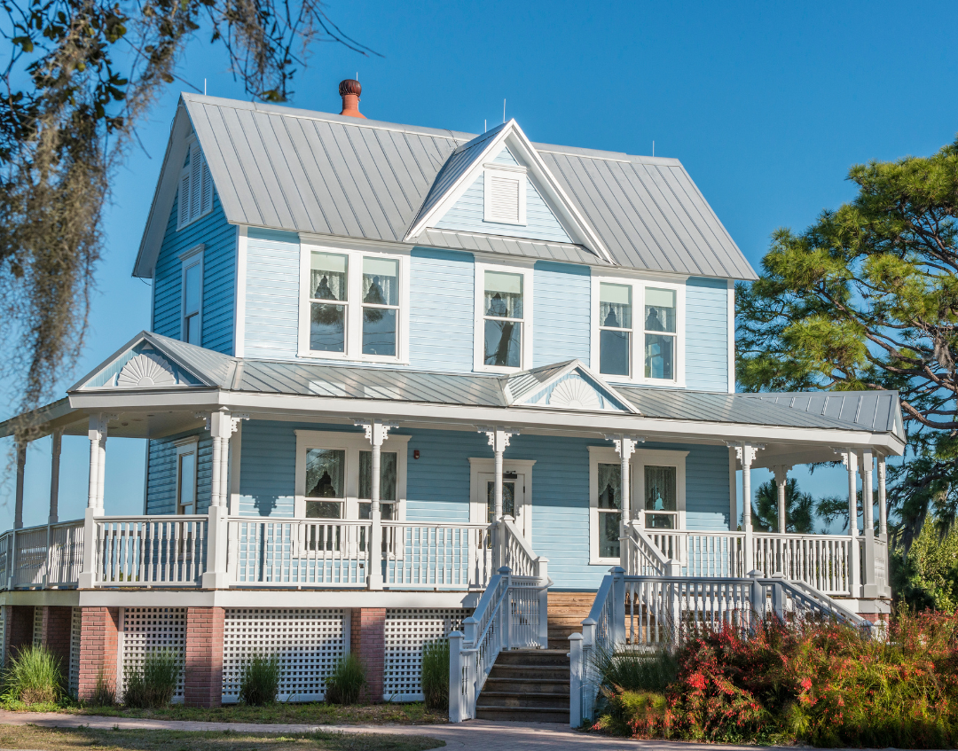 Two-story blue house with white trim and a wraparound porch. 