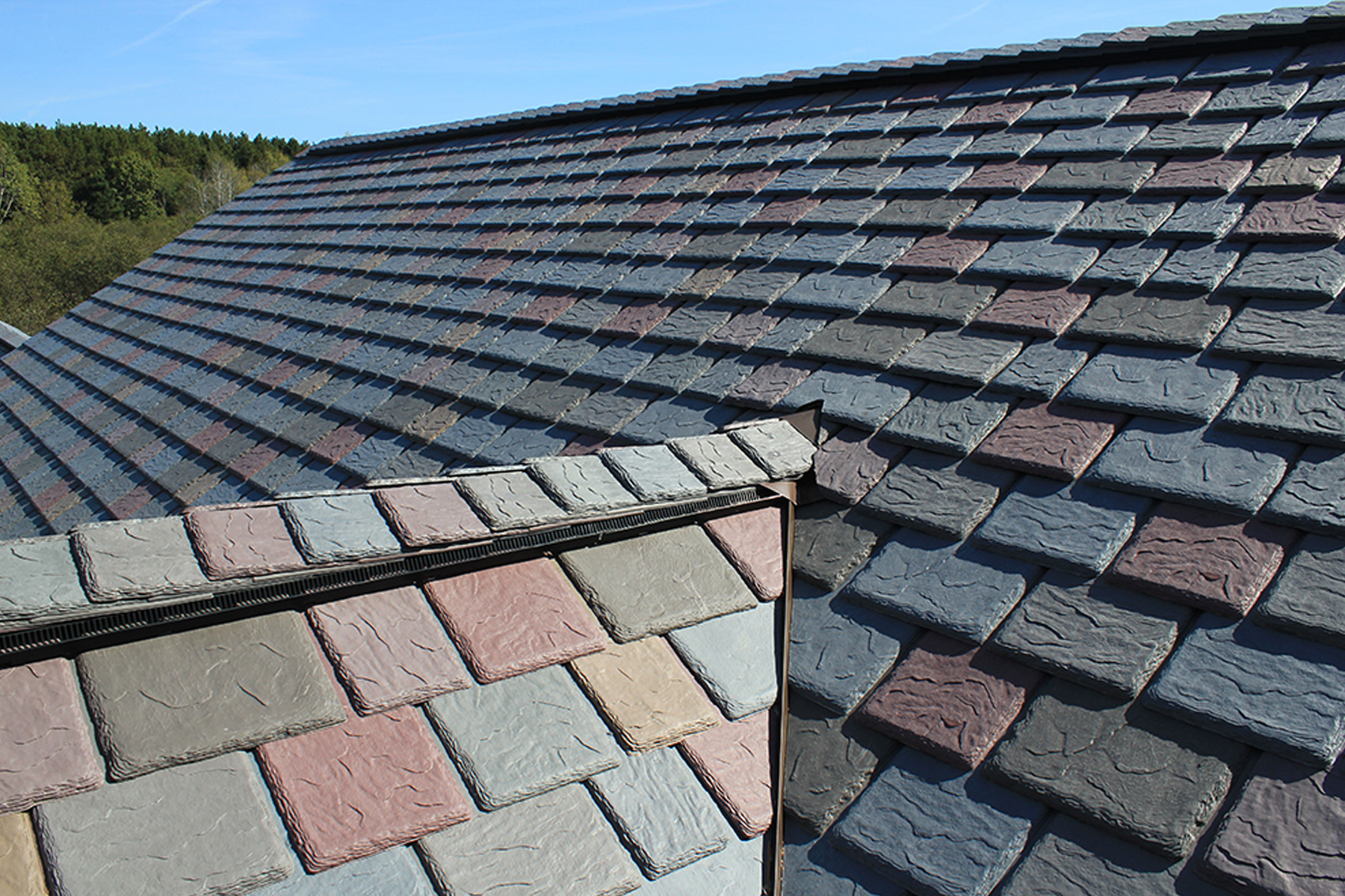 Detailed view of a multi-colored slate roof with a blend of gray, blue, and pink tiles. 