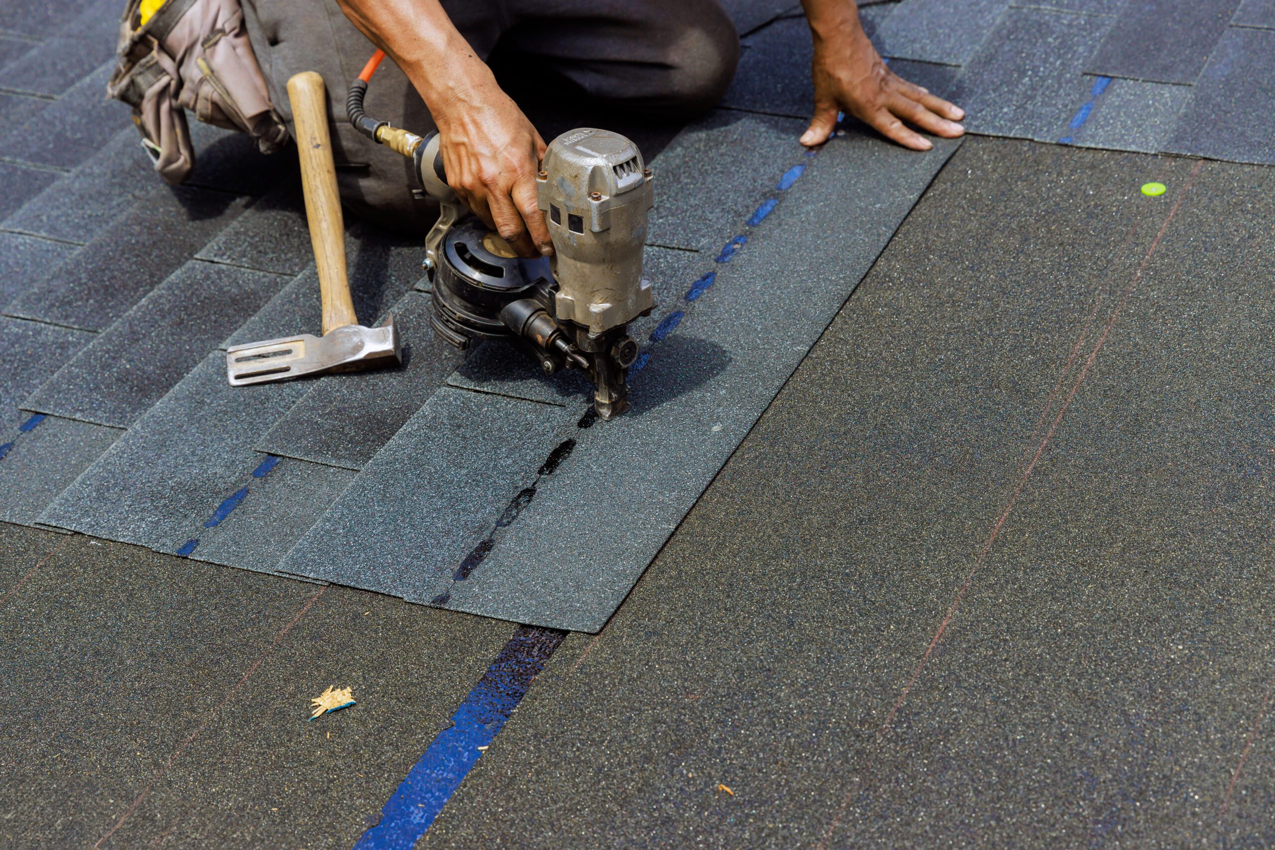 A roofing contractor works with new asphalt shingles during a roof installation.